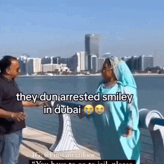 a man and a woman are standing next to each other in front of a body of water and a city skyline .