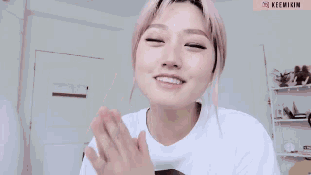 a woman with pink hair is wearing a white shirt with the name keemikim on the bottom right