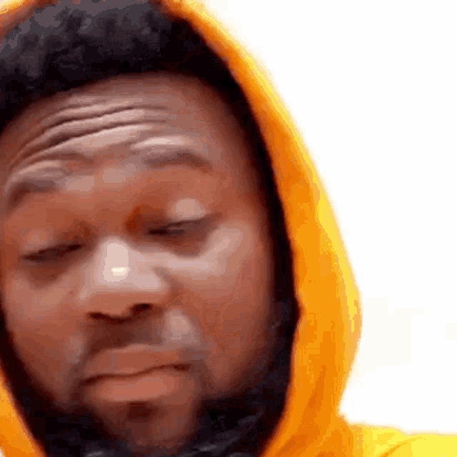 a man with a beard wearing an orange hoodie is making a funny face .