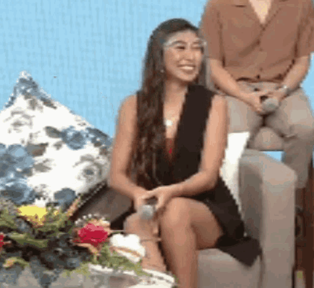 a woman is sitting in a chair with flowers in front of her .