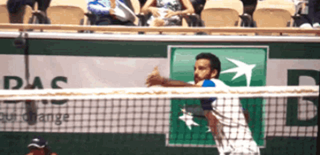 a man is playing tennis in front of a das sign
