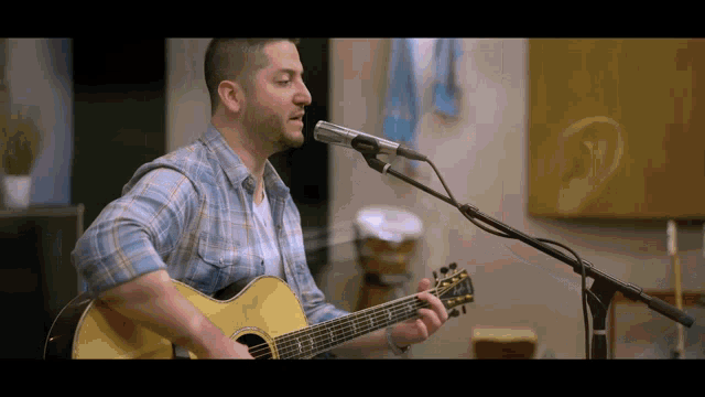a man is singing into a microphone while playing a guitar
