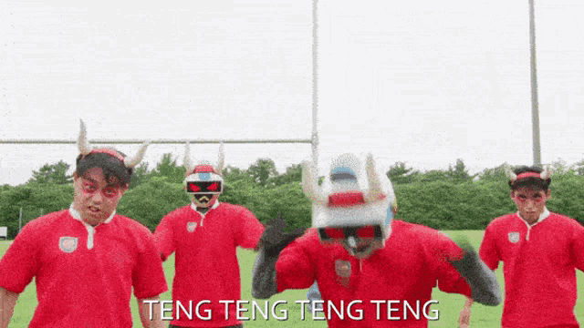 a group of men wearing red shirts and horned helmets are standing on a field with the words teng teng teng teng below them