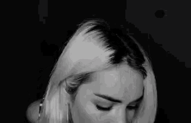 a close up of a woman 's face in a black and white photo with her eyes closed .