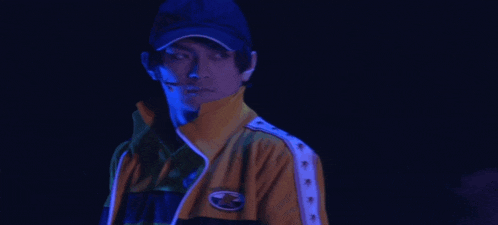a man wearing a blue hat and a yellow jacket has a sticker on his jacket that says tokyo