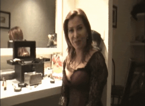 a woman is standing in front of a mirror looking at herself in a mirror