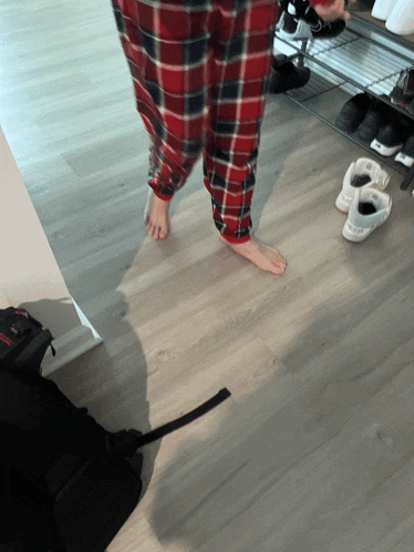 a person wearing plaid pants is standing on a wood floor