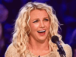 a woman with blonde hair is singing into a microphone .