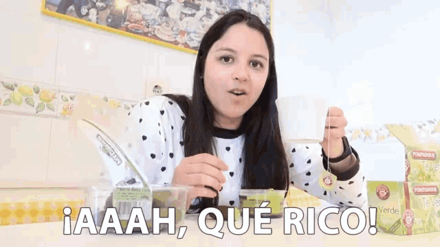 a woman sitting at a table with a box of green tea in front of her that says iaaah que rico