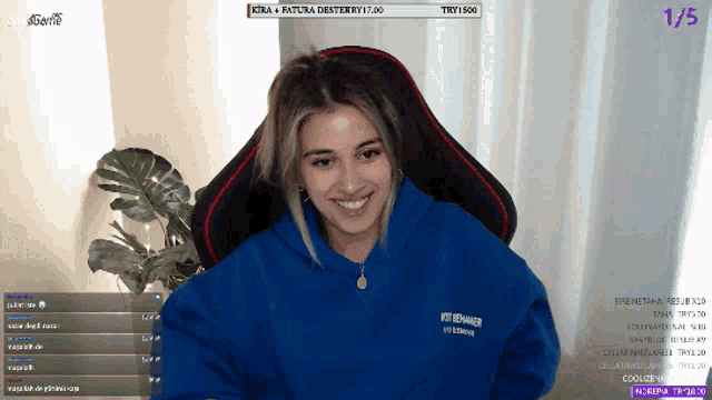 a woman in a blue hoodie is smiling in front of a purple screen