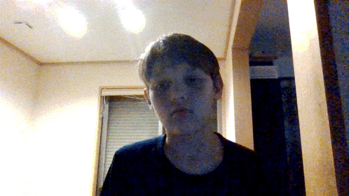 a boy in a black shirt is standing in a dark room