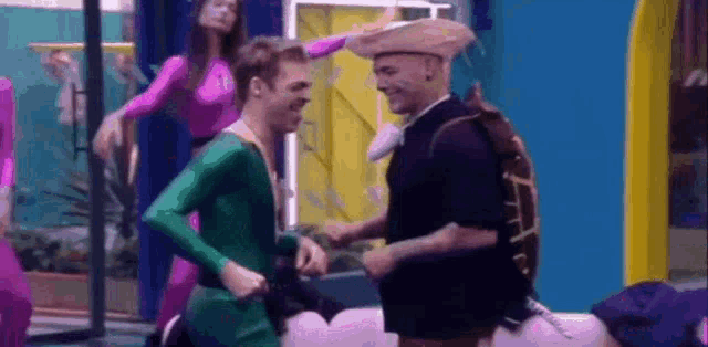 a man in a green shirt and a man in a turtle costume are dancing together .