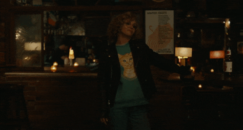 a woman in a leather jacket is standing in front of a sign that says i 've lit dicks on fire