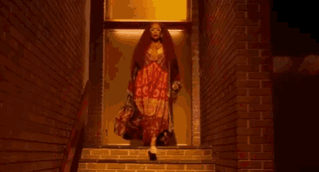 a woman with long red hair and glasses is standing in a dark room .
