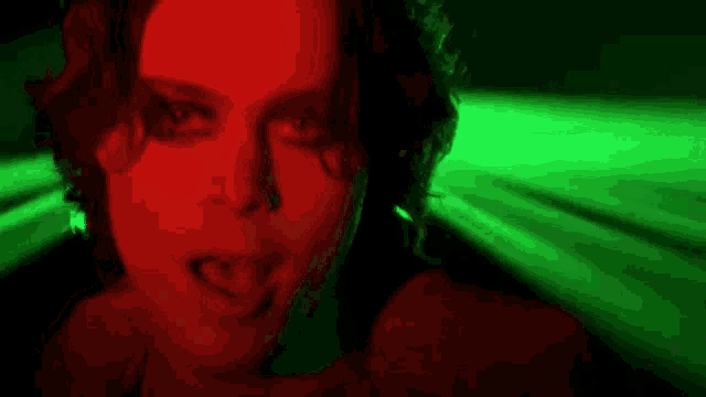 a close up of a woman 's face in a dark room with red and green lights behind her .