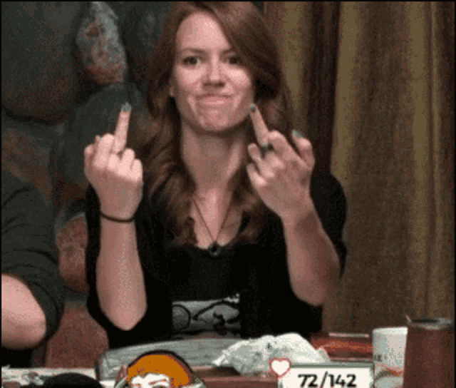 a woman sitting at a table with a sign that says 72/142 on it