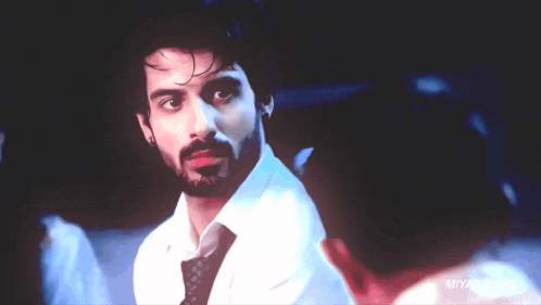 a man in a white shirt and tie is looking at a woman in a dark room with the name miyasaliha on the bottom