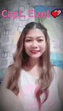a woman with long hair is smiling in front of a wall with the name capt eizel on it .