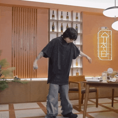 a man in a black shirt is dancing in a room with a sign that says " k " on it