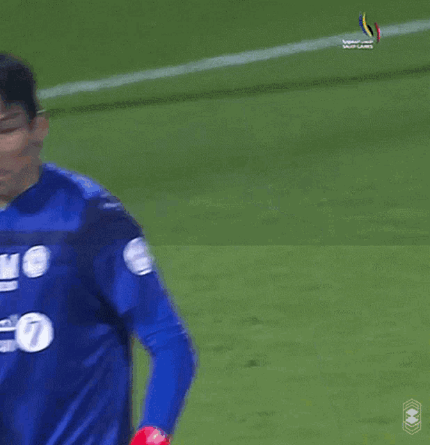 a blurry picture of a soccer player wearing a blue jersey with a white logo on it