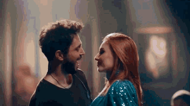 a man and woman are looking at each other in a dark room .