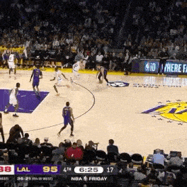 a group of basketball players are playing basketball on a court in front of a crowd .