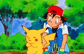 a boy in a red hat is kneeling next to a pikachu in a forest .