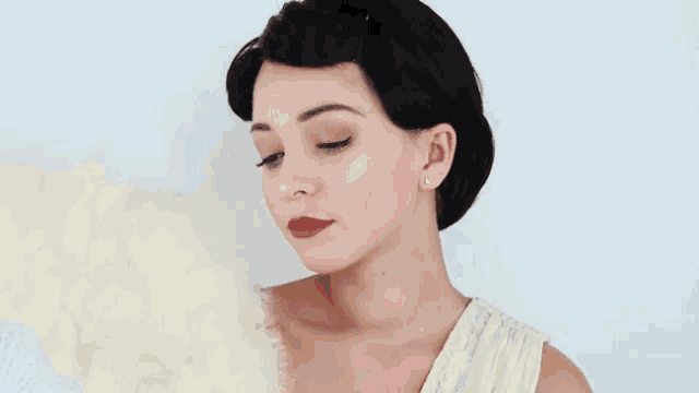 a woman in a white dress is applying makeup to her face