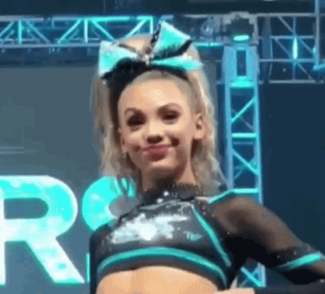 a cheerleader wearing a blue and black outfit and a bow on her head .