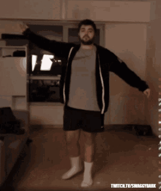 a man with a beard is dancing in front of a screen that says twitch.tv/swaggy bark