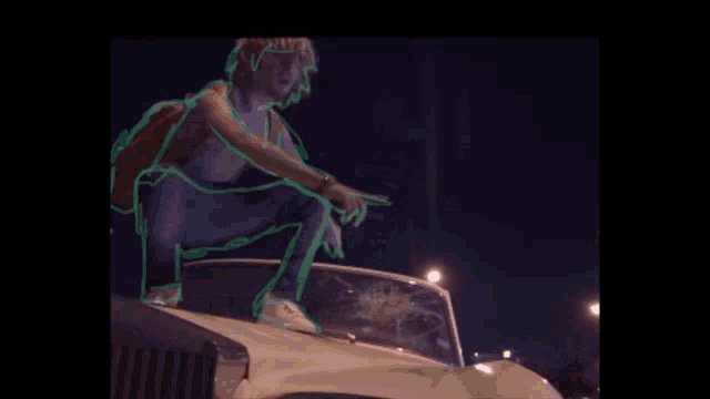 a man is sitting on the hood of a car