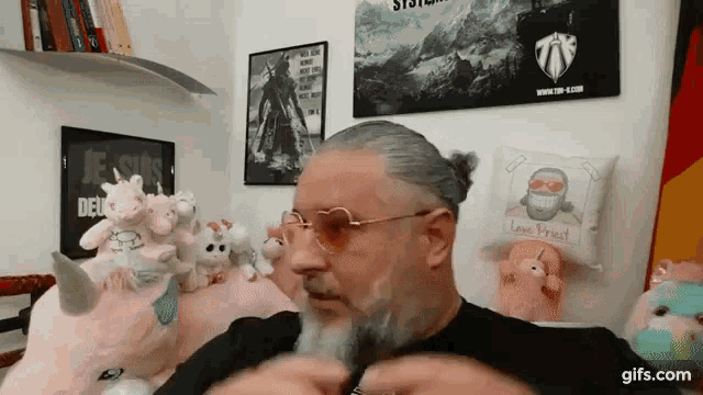 a man with glasses and a ponytail is standing in front of stuffed unicorns