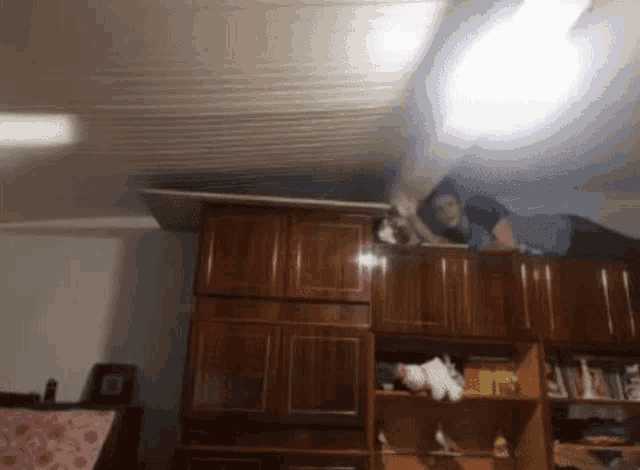 a man is laying on top of a wooden shelf in a living room .