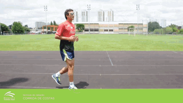 a man is running on a track with a coca cola shirt on