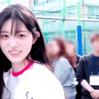 a woman in a white shirt with a red collar is smiling while standing in front of a group of people .