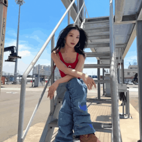 a woman in a red tank top sits on a set of steps