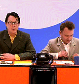 two men are sitting at a desk with a phone on it