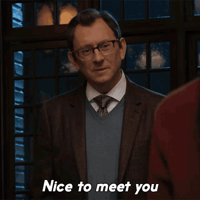 a man in a suit and tie shakes hands with another man and says nice to meet you
