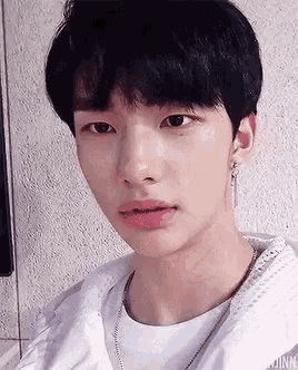 a close up of a person 's face with a white shirt and earrings .