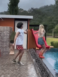 two girls are playing in a pool with a slide