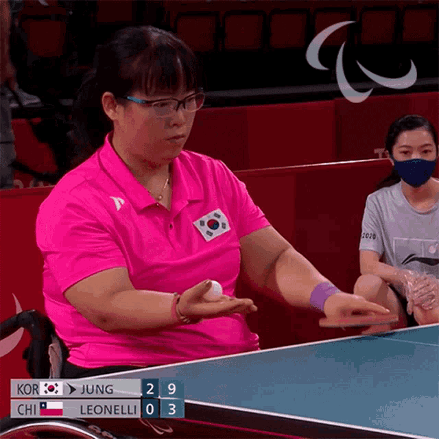 a woman in a pink shirt is playing ping pong against chi