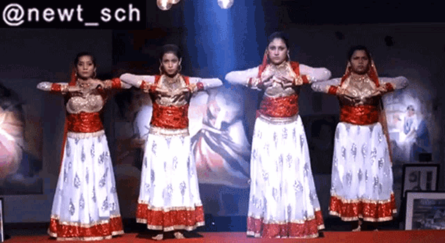 a group of women are performing in front of a sign that says newt sch