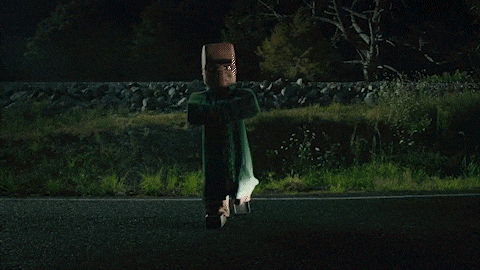 a car is driving down a road at night with a scarecrow flying overhead