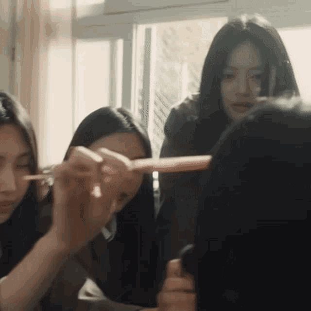 a group of young women are sitting around a table and one of them is holding a pink pencil
