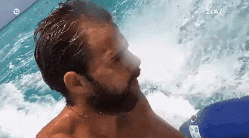 a man with a beard is swimming in a pool with the number 12 on the bottom right