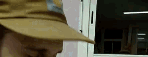 a man wearing a hat is standing in front of a window in a room .