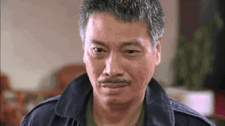 a man with a mustache is wearing a blue jacket and making a funny face .