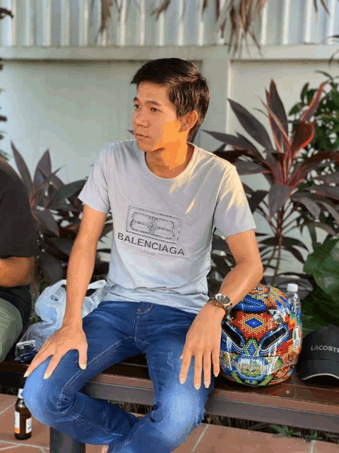 a man is sitting on a bench wearing a balenciaga shirt