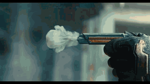 a person holding a gun with smoke coming out of the barrel