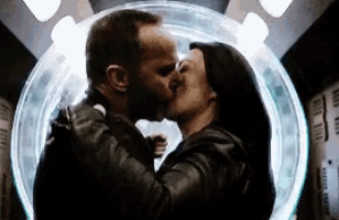 a man and a woman are kissing in front of a glowing circle .
